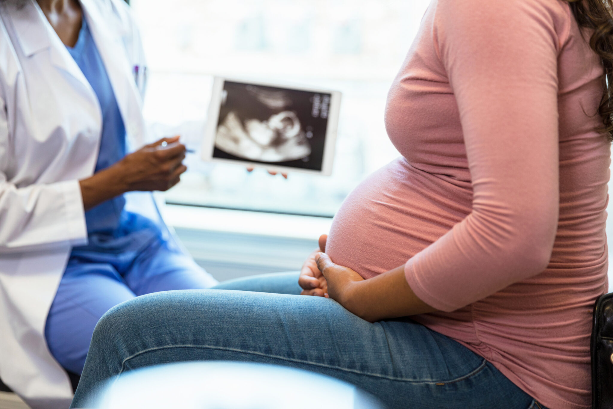 pregnant woman speaking with her daughter about an ultrasound scan the doctor is holding up
